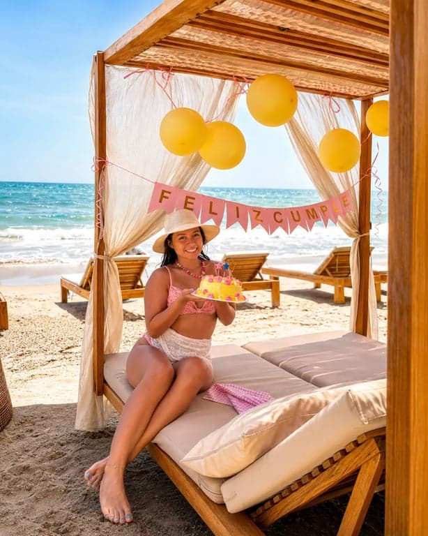 Montaje de cumpleaños con globos y pastel en una cama de playa de Nakawa Beach Club.