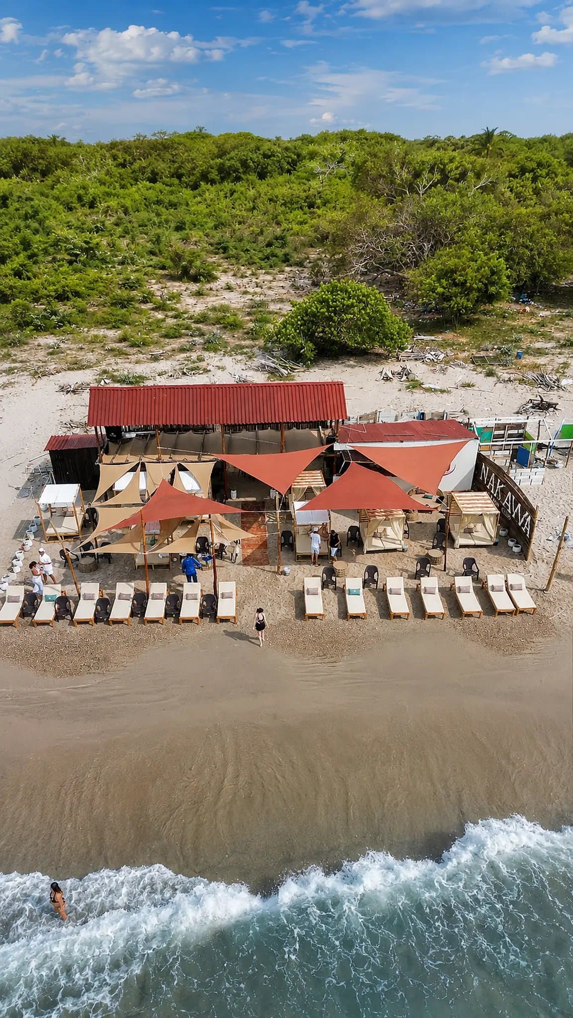 Vista aérea de Nakawa Beach Club con su letrero, camastros y velas de sombra en Playa Linda.